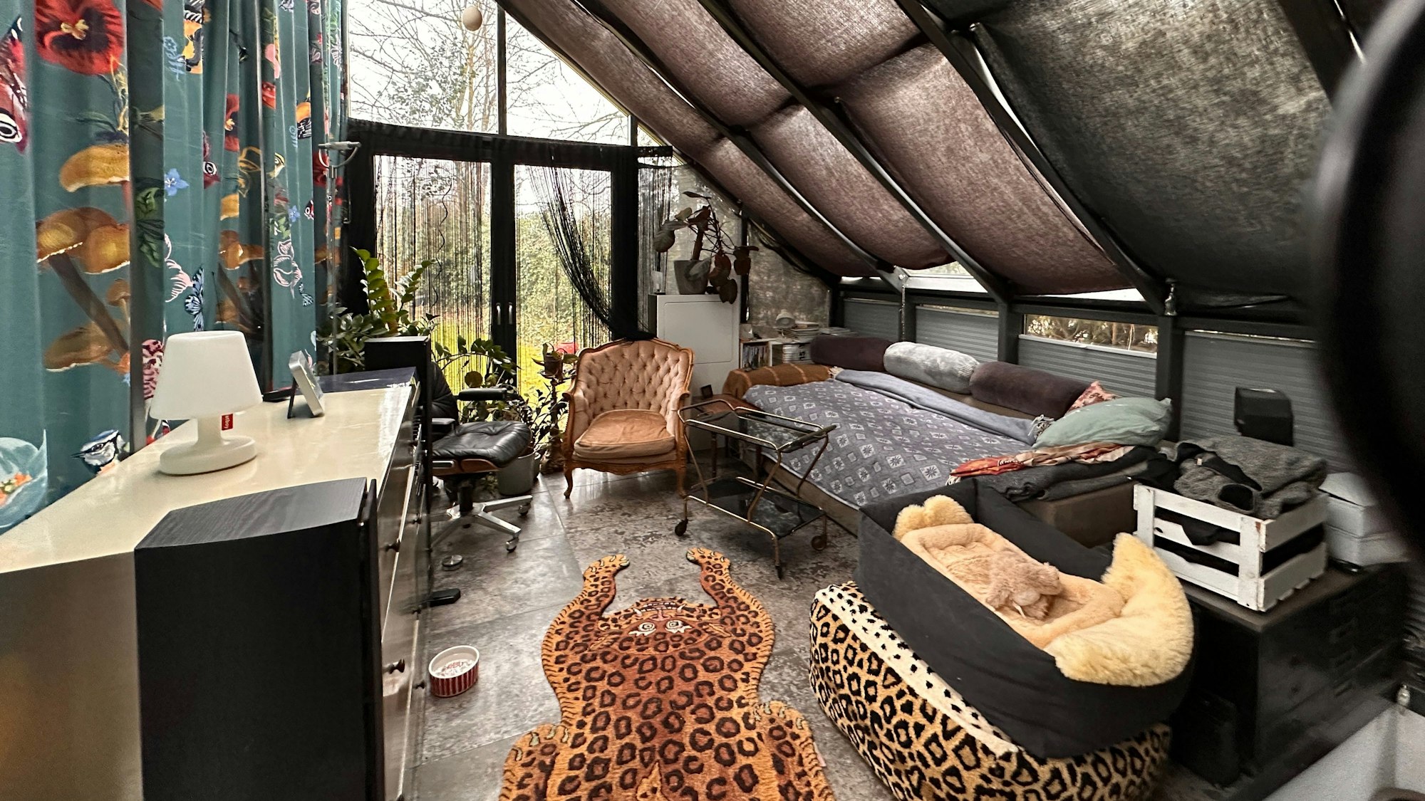 Blick in einen Raum mit Sofa, Sesseln, Sideboard und einer Terrassentür mit bodentiefen Fenstern