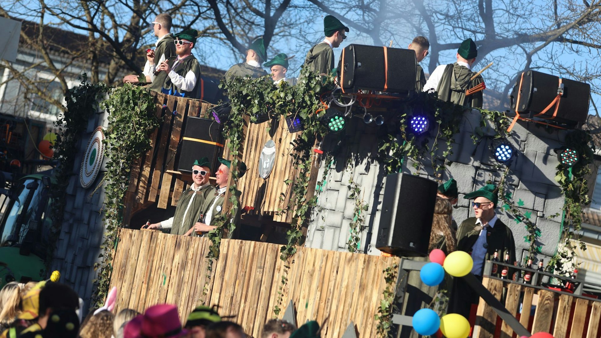 Junge Leute in grünen Kostümen auf einem Karnevalswagen.