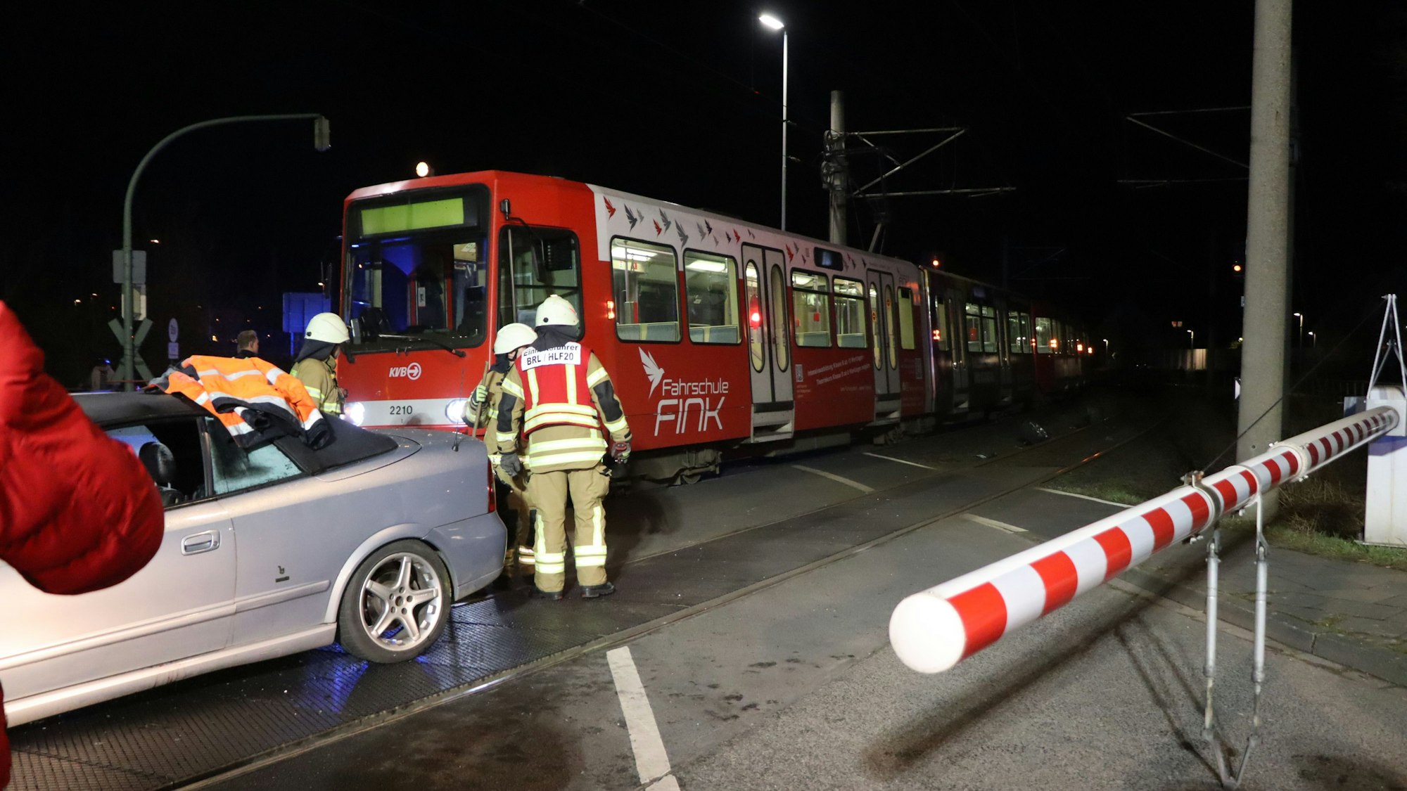 Das Bild zeigt einen Bahnübergang, ein verunglücktes Auto und eine Straßenbahn.