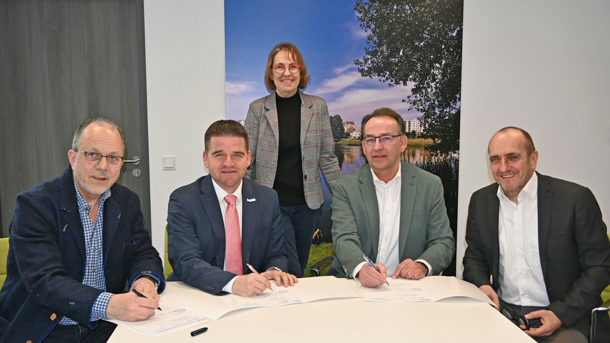 Im Beisein von Fachbereichsleiterin Waltraud Leersch (stehend) unterzeichnen den Vertrag (vorne, von links): der Technische Beigeordnete Heinz-Peter Witt, Bürgermeister Holger Jung sowie die beiden Vorstände der BürgerEnergie Rhein-Sieg eG, Thomas Schmitz und Dietmar Hansen.