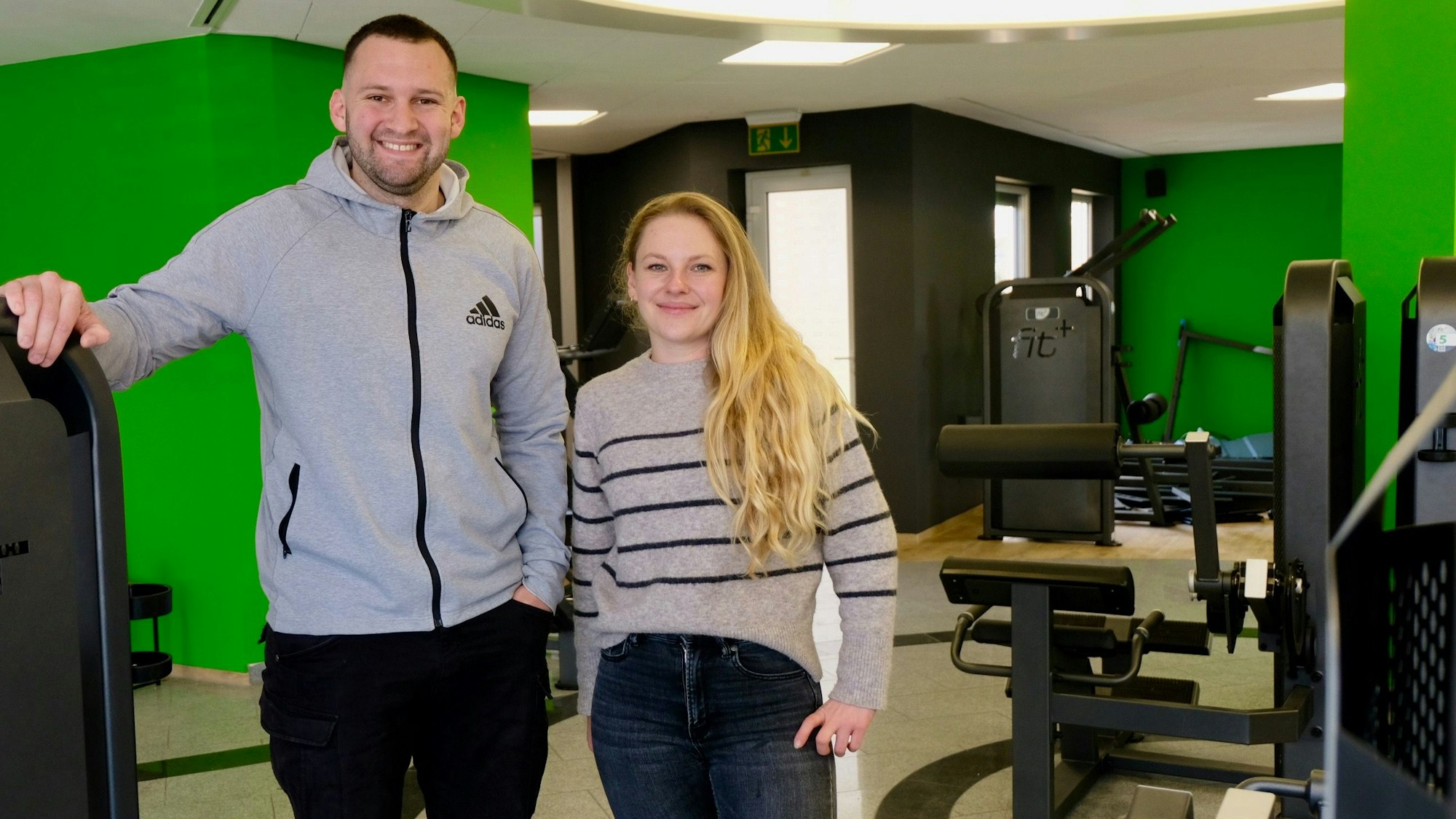 Ein Mann und eine Frau stehen in einem neuen Fitnessstudio.