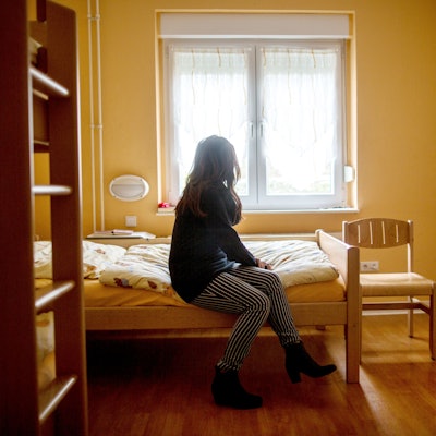 Eine Frau sitzt im Frauenhaus auf einem Bett. Das Gleichstellungsministerium in NRW möchte Frauenhäuser stärker fördern. +++ dpa-Bildfunk +++