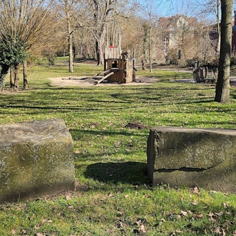 Zu sehen ist ein Park mit Findlingen und einem Spielplatz.