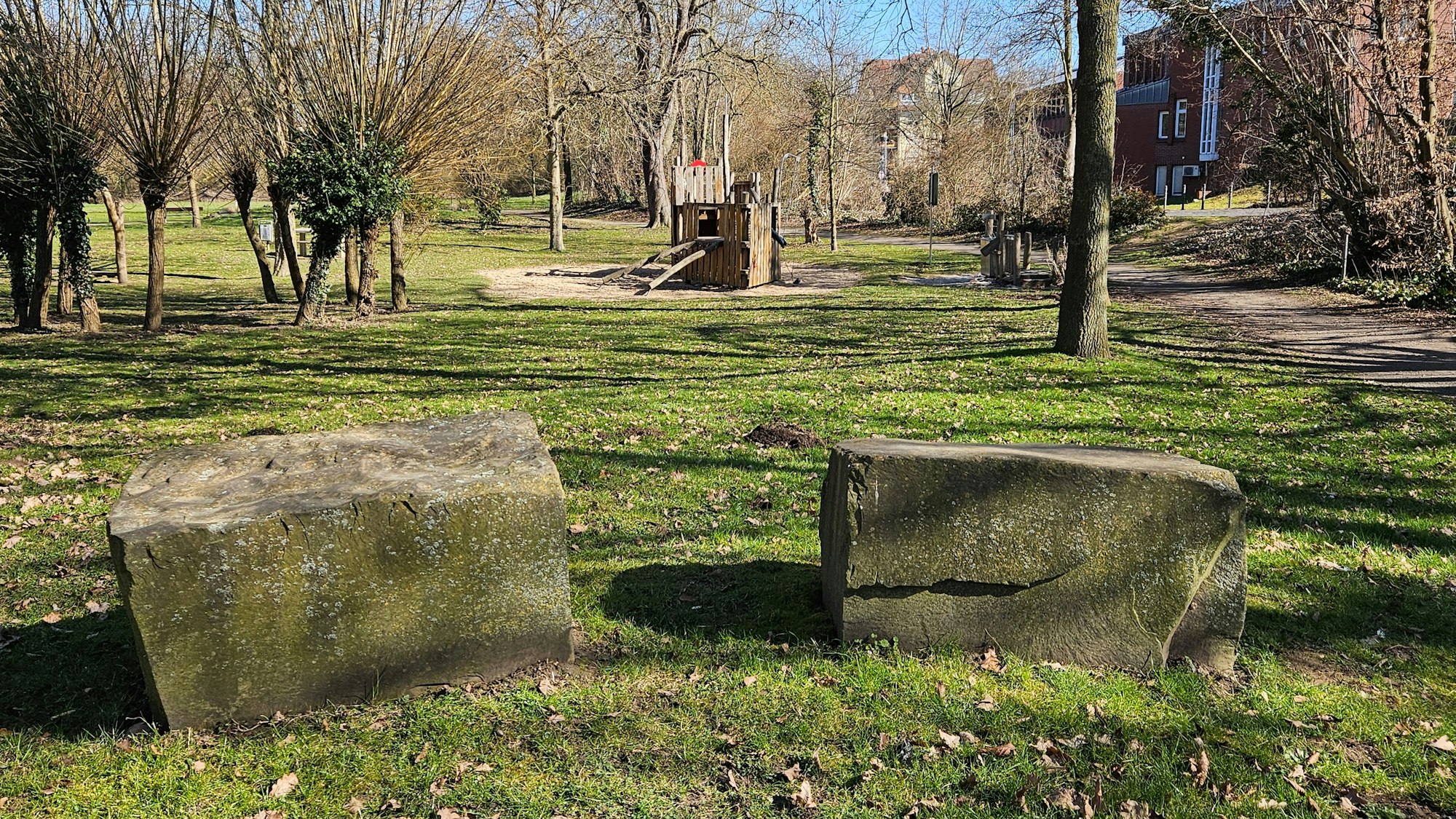 Zu sehen ist ein Park mit Findlingen und einem Spielplatz.