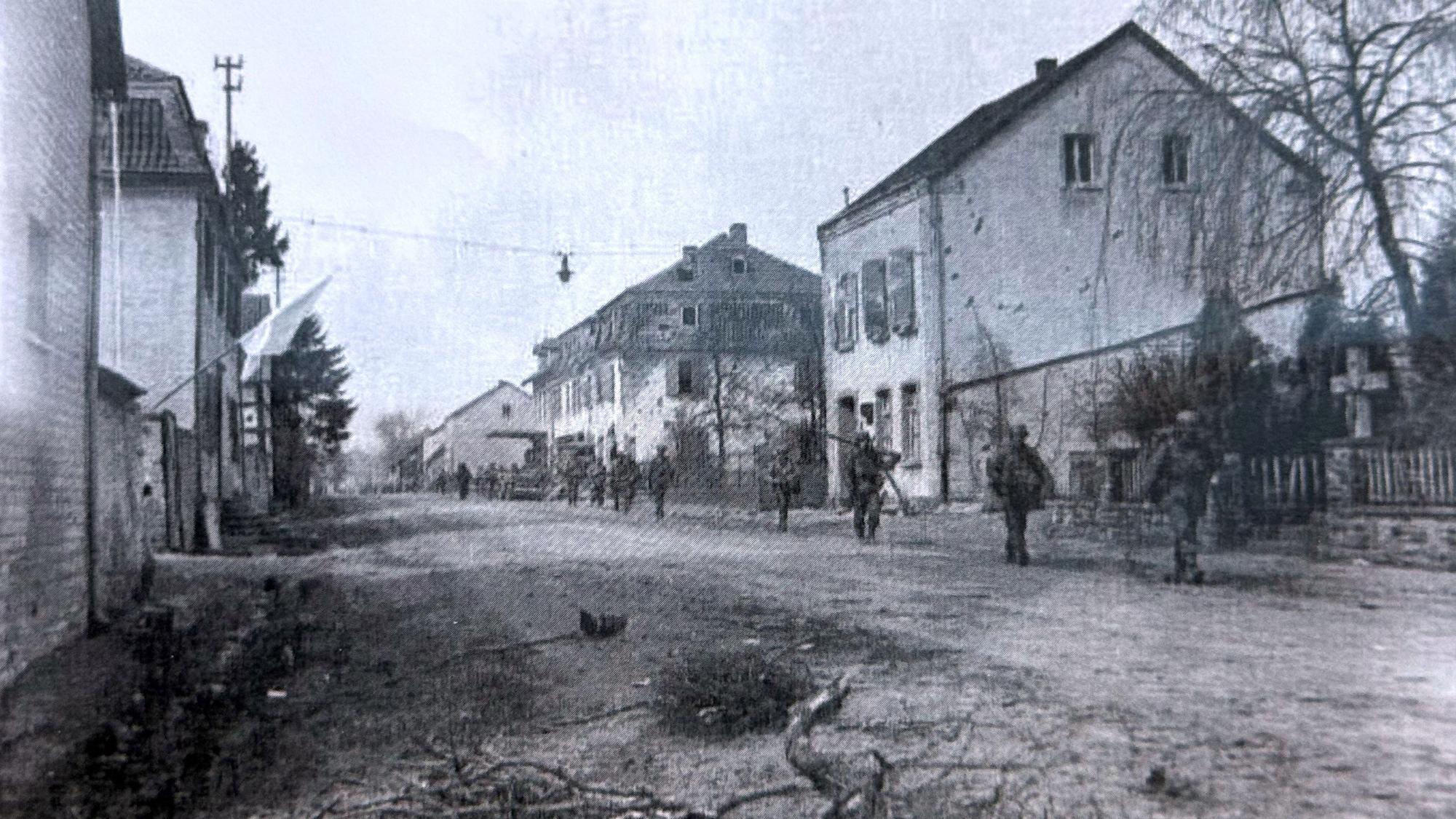 US-Soldaten gehen über eine Straße, die von Häusern gesäumt ist.
