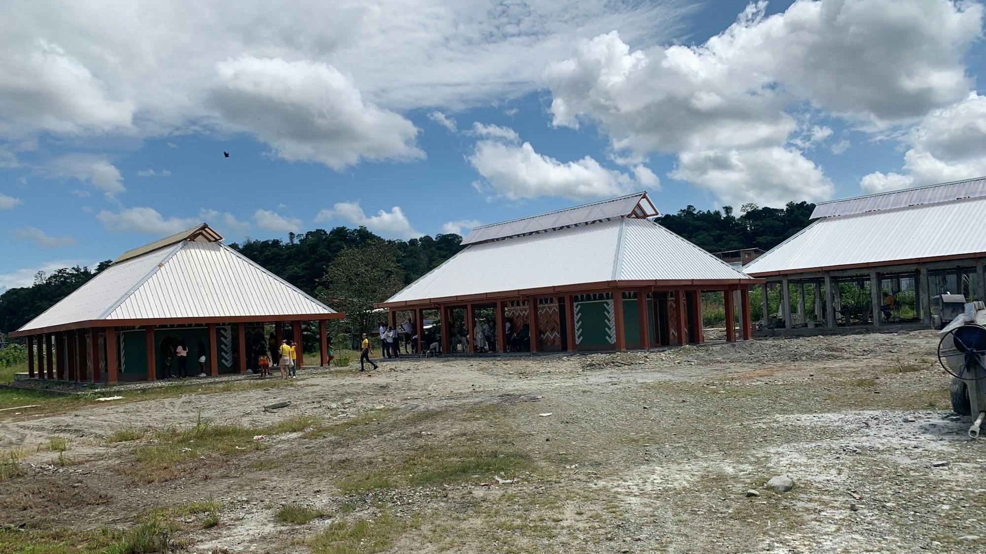 Auf einer Brachfläche stehen drei einstöckige Gebäude.