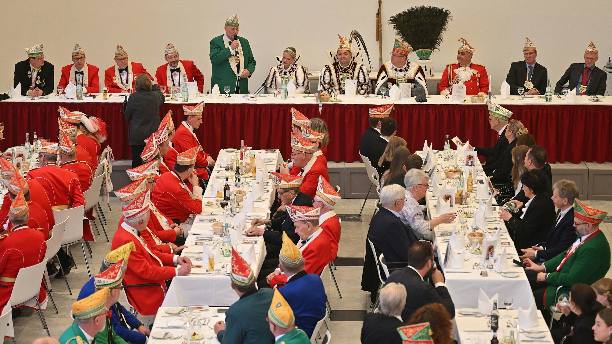Ein Mann im grünen Jackett steht an einem Tisch auf der Vorderseite des Banketts zum Prinzenessen 2025 in Bergisch Gladbach.