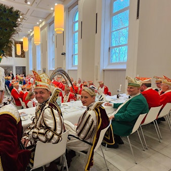 Bauer Michael, Prinz Christian I. und Jungfrau Steffi sitzen an einem Tisch beim Prinzenessen im Kardinal-Schulte-Haus.