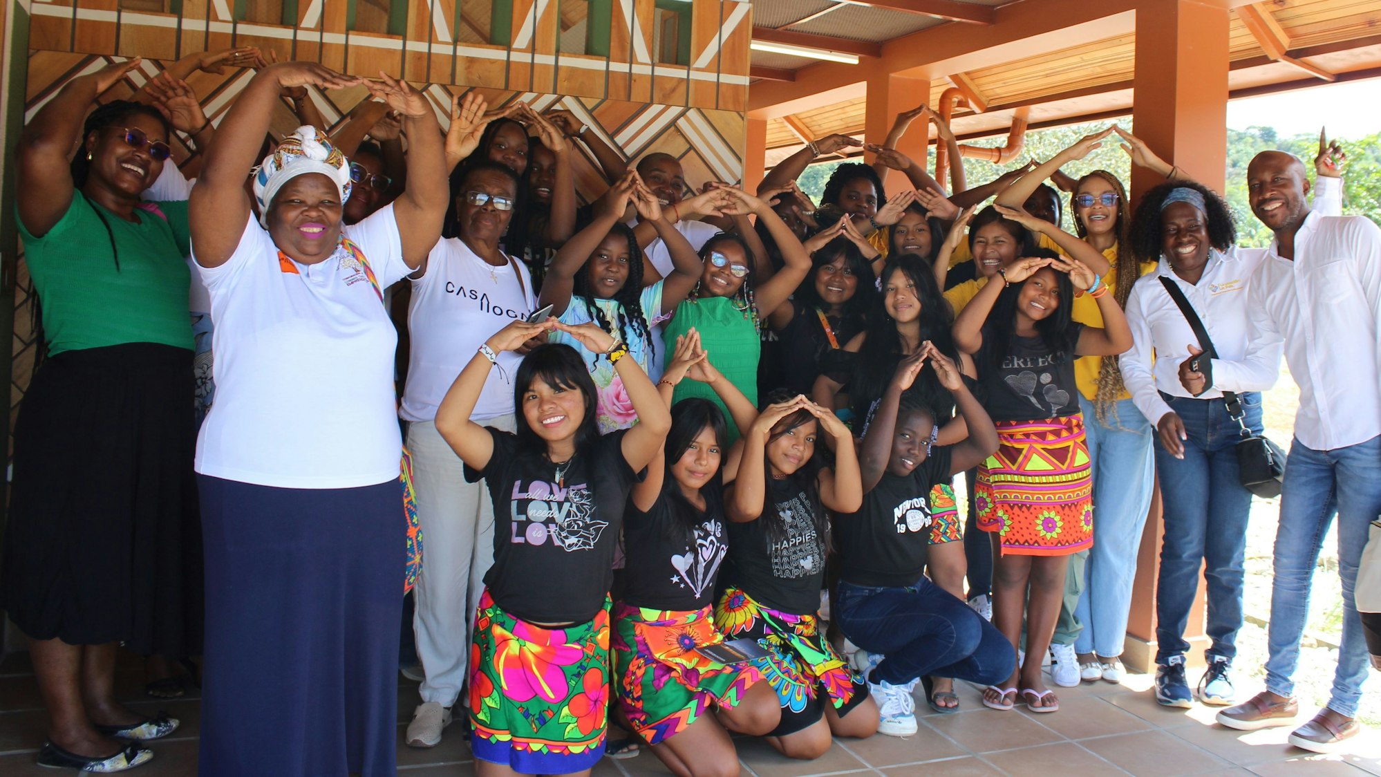 Frauen und Mädchen haben die Hände zu einem Dach über dem Kopf geformt.