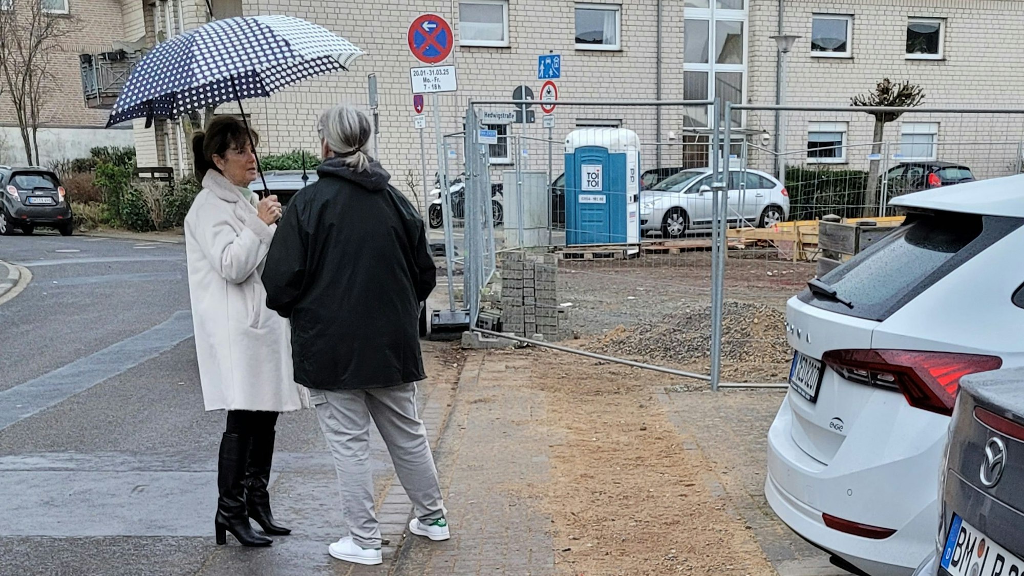 Ein Gehweg, dahinter ist ein Zaun zu sehen.
