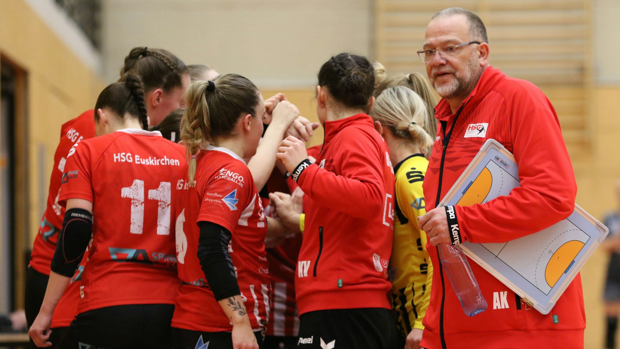 Andreas Kunzke hat ein Klemmbrett unter dem Arm und geht an seiner feiernden Mannschaft vorbei.