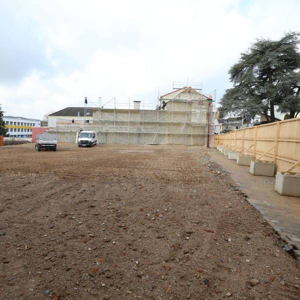 Eine große, mit Sand bedeckte Fläche, links im Hintergrund das ehemalige Gebäude der Post in Bad Honnef.