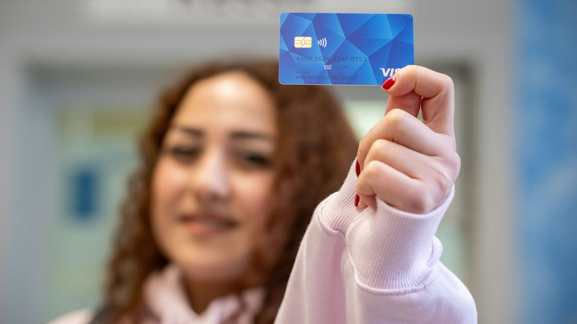Eine Frau aus Armenien hält das Muster einer Bezahlkarte in die Kamera.