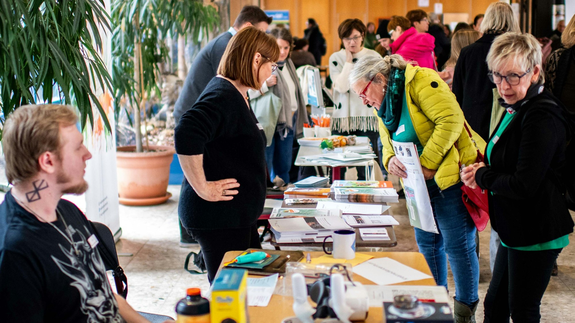 Beiderseits eines langen Tischs schauen sich Lehrerinnen und Lehrer Informationsmaterial an.
