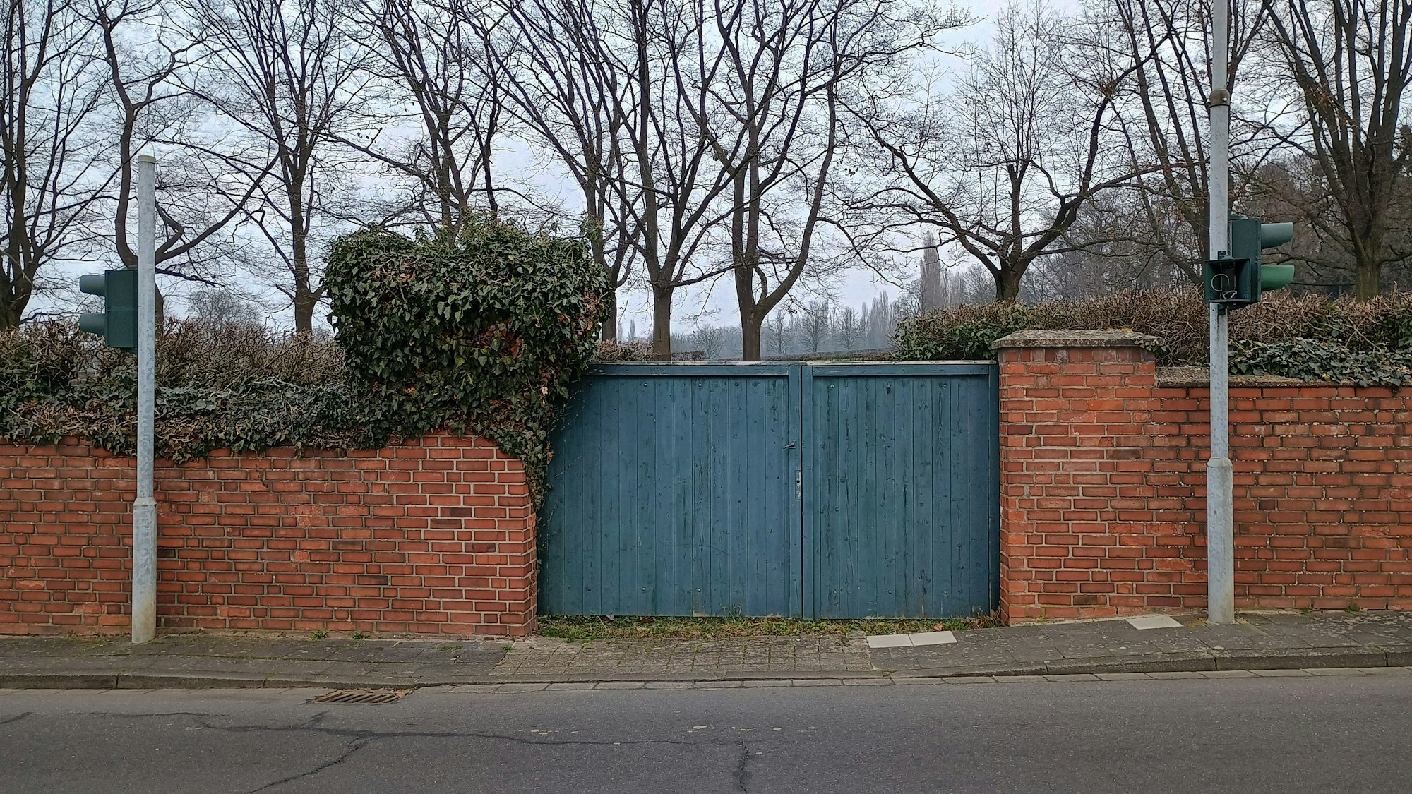 Auf dem Bild ist das Tor zu einer Pferdewiese zu sehen, rechts und links stehen die Masten der Ampel.