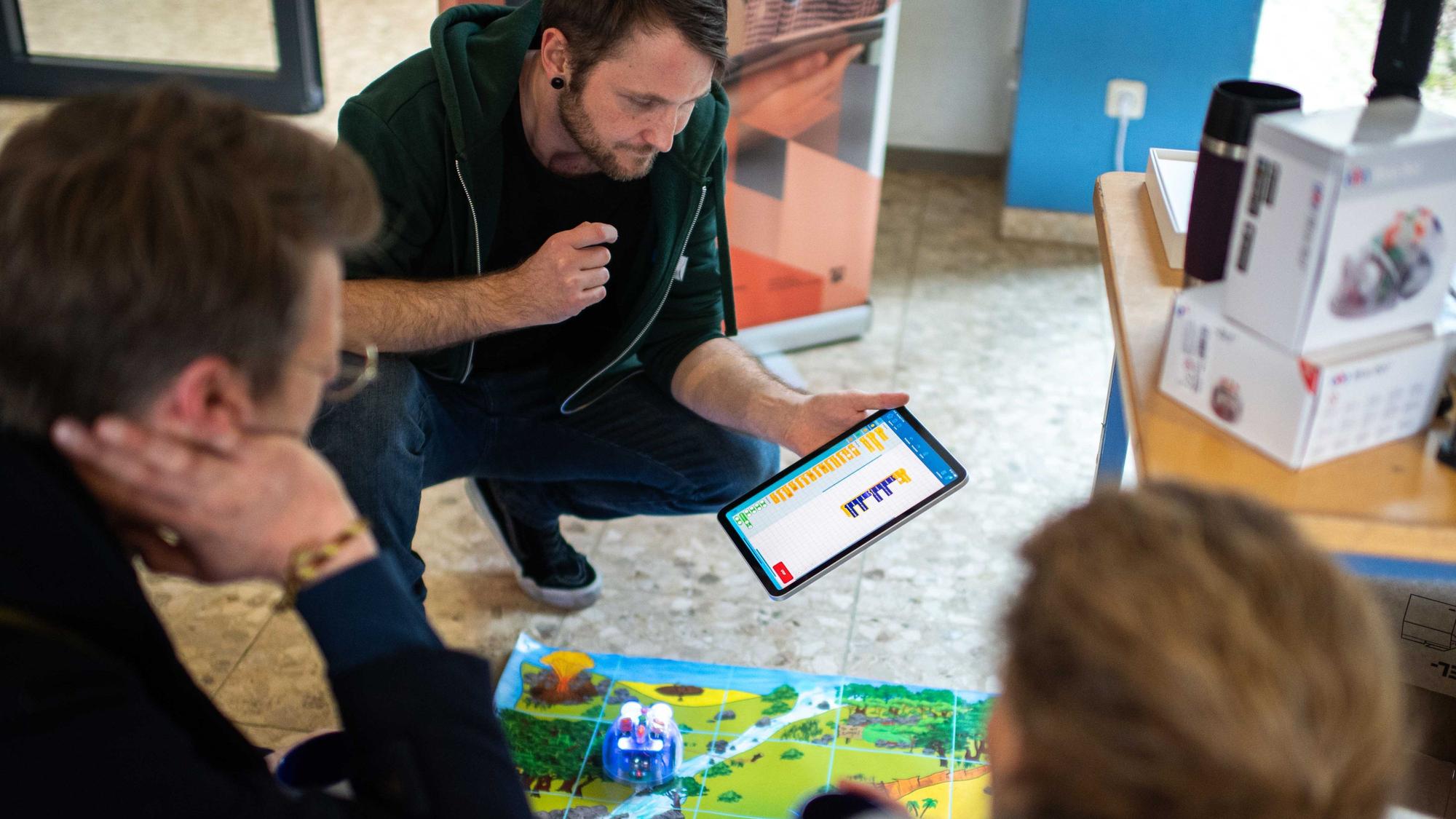 Drei Personen schauen gemeinsam auf ein Tablet.