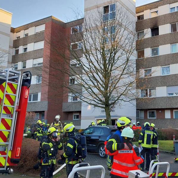Einsatzkräfte der Feuerwehr vor einem Hochhaus.