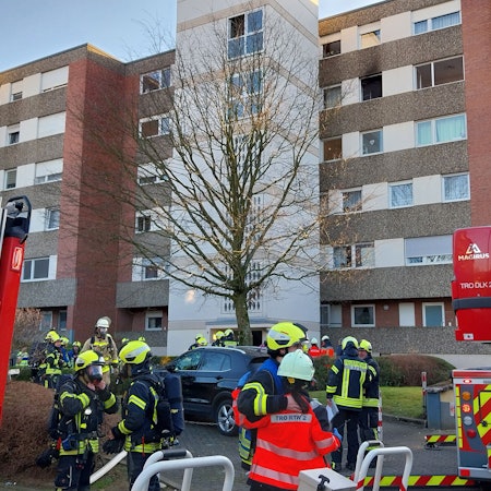 Einsatzkräfte der Feuerwehr vor einem Hochhaus.