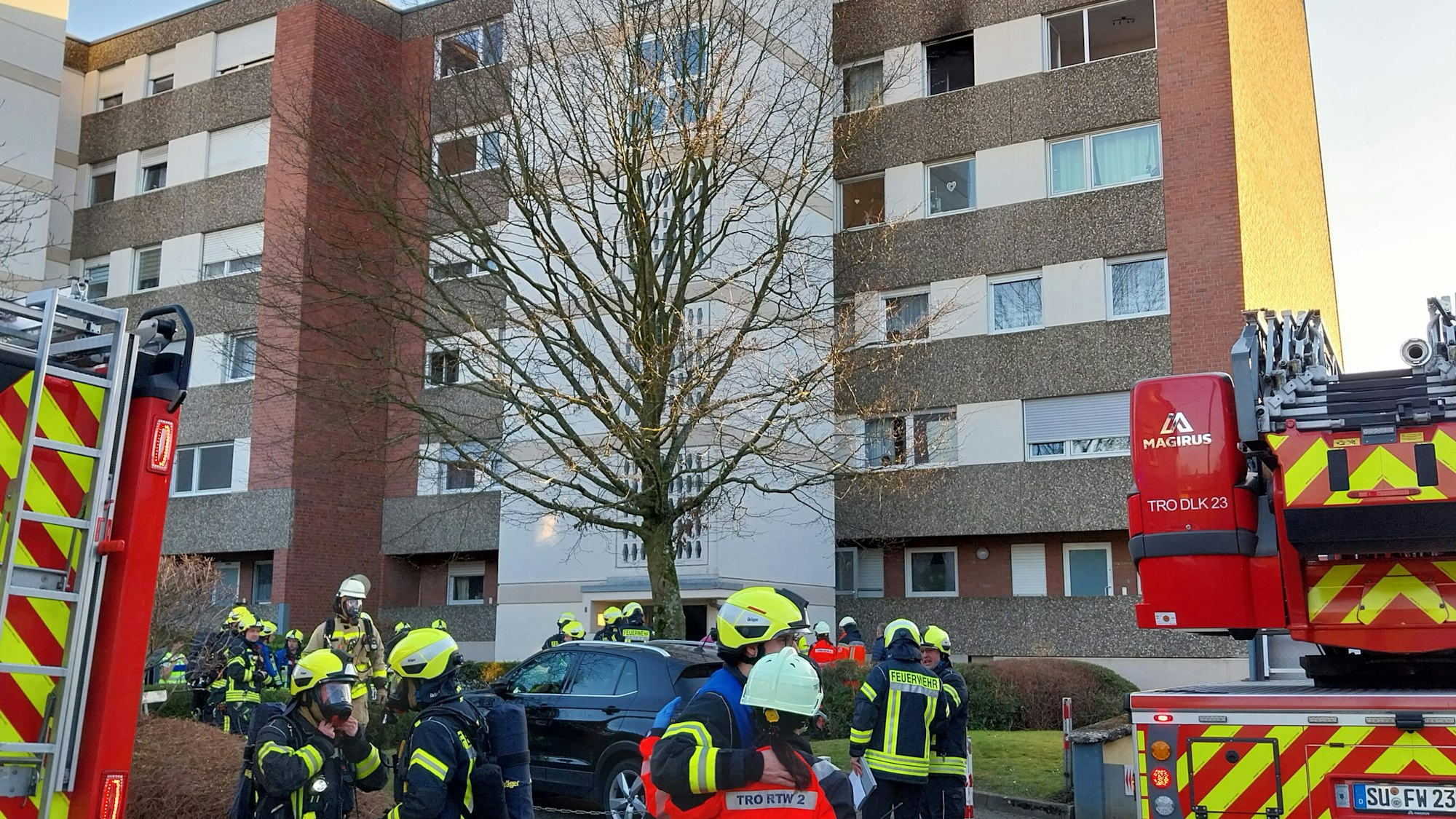 Einsatzkräfte der Feuerwehr vor einem Hochhaus.