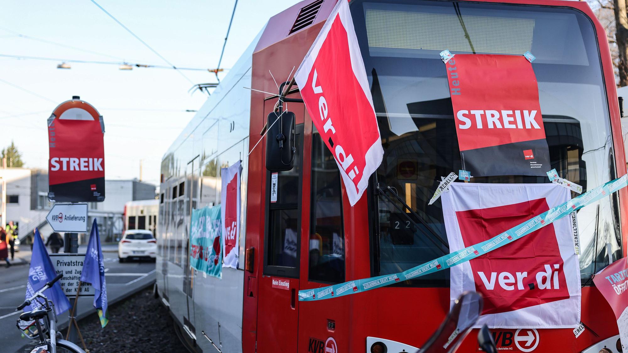Eine mit Streik-Plakaten beklebte Straßenbahn der Kölner Verkehrs-Betriebe (KVB) steht vor dem Bahndepot. (Archivbild)
