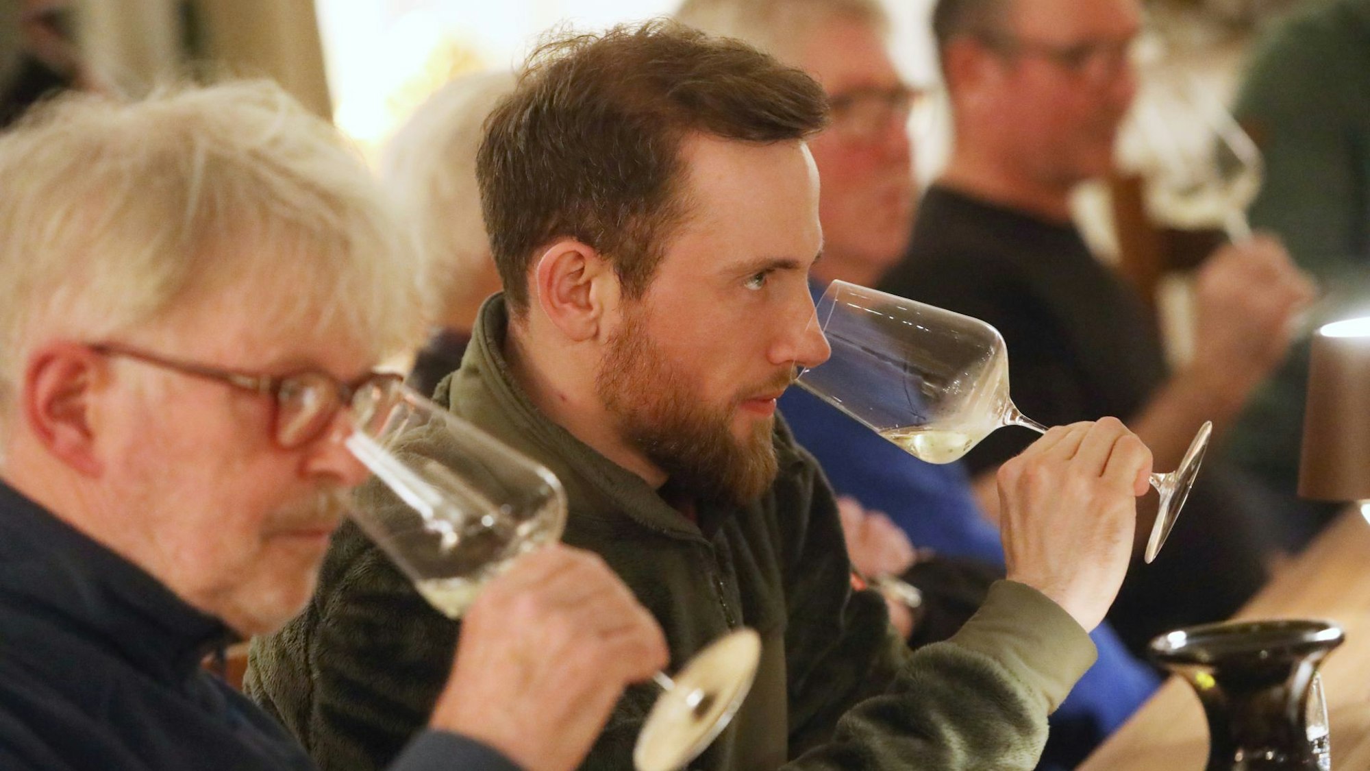 Die Winzer riechen bei der Weinprobe an ihren Gläsern.