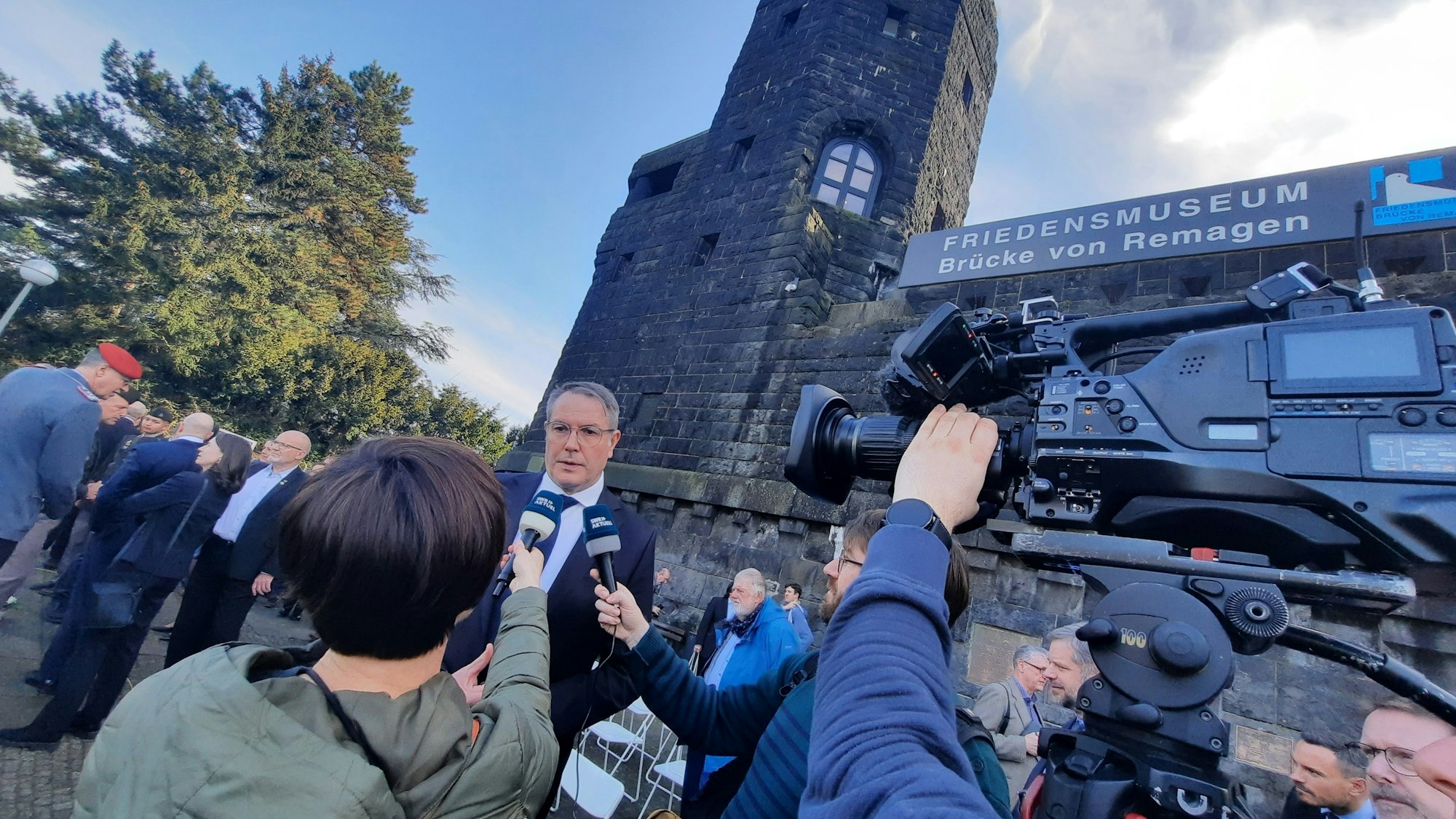 Journalisten interviewen vor den Türmen der Remagener Brücke den Ministerpräsidenten von Rheinland-Pfalz.