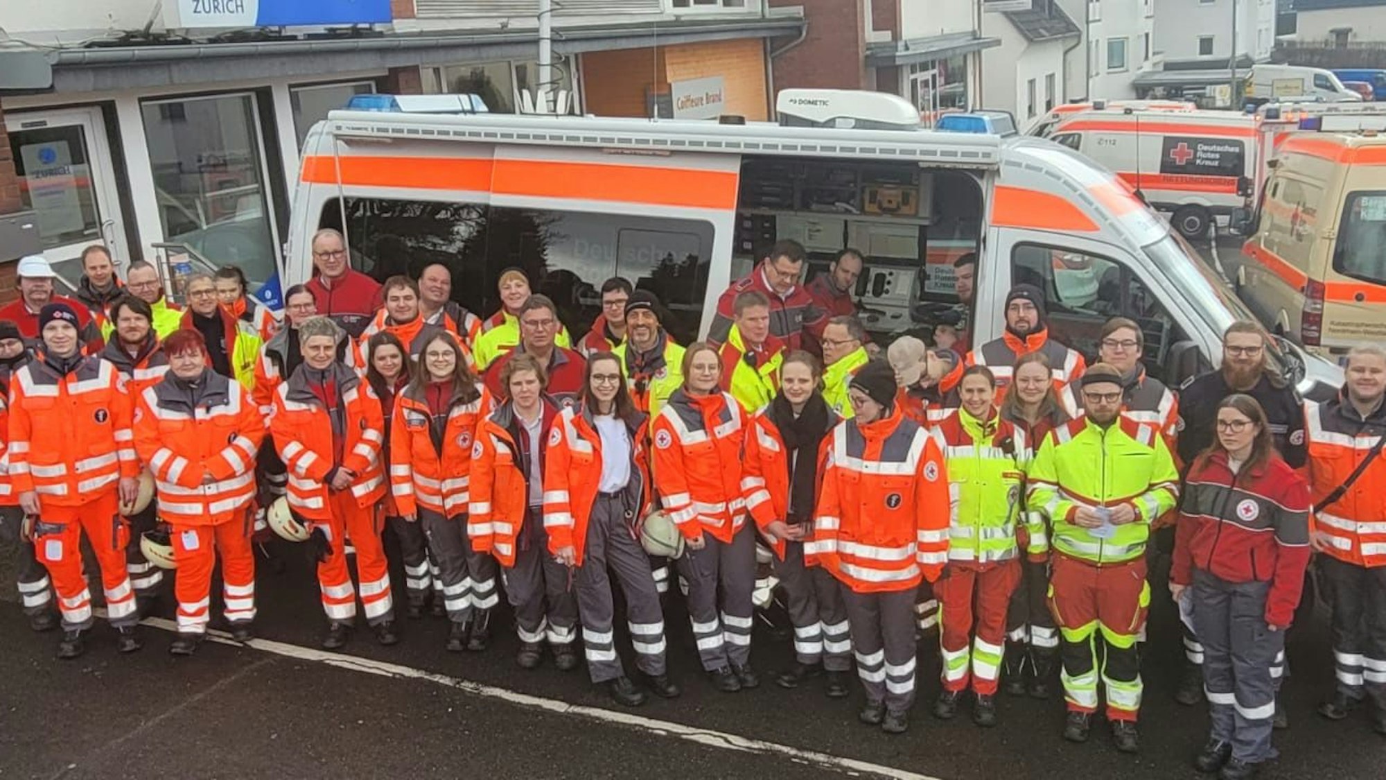 DRK-Einsatzkräfte stehen vor Einsatzfahrzeugen.