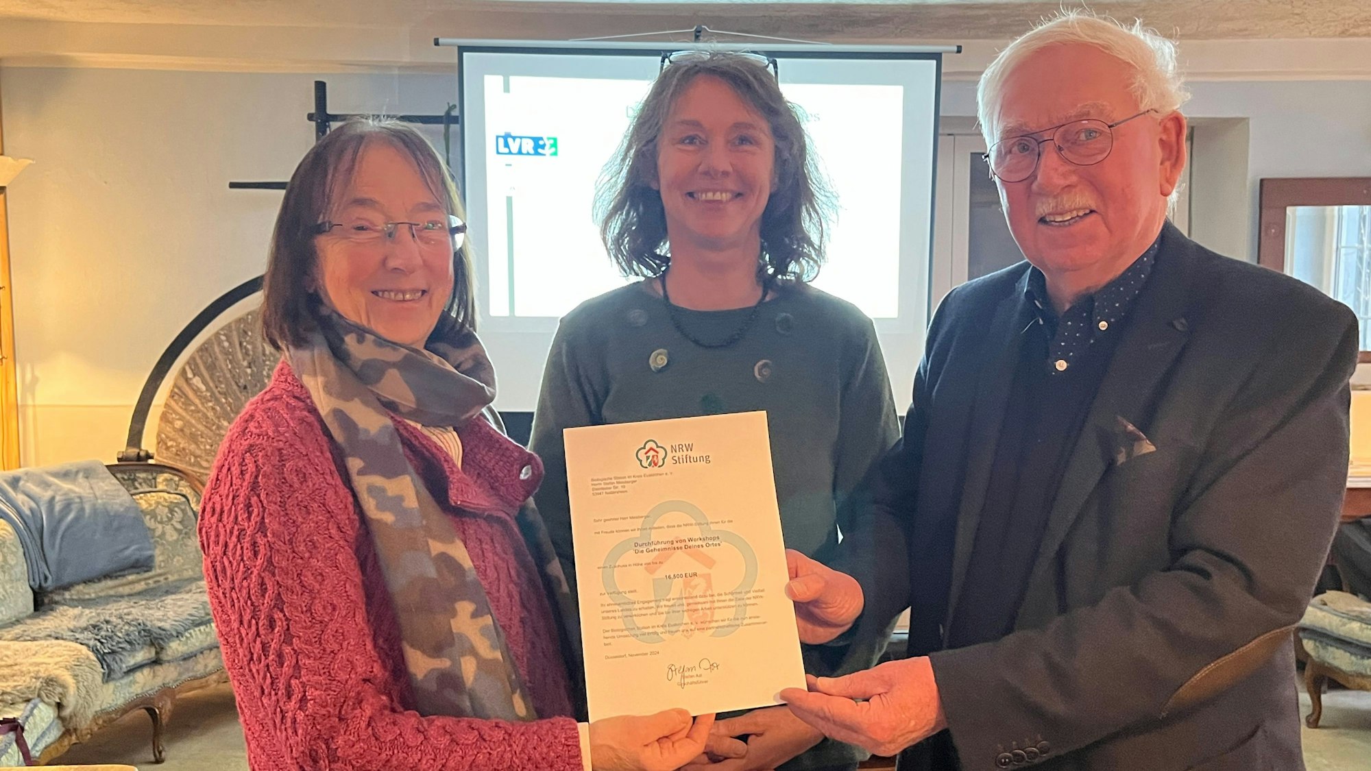 Veronika Neumann, Elke Sprunkel und Ralf Sawatzki halten ein Schriftstück in die Kamera.