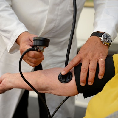 Ein Hausarzt misst in seiner Praxis den Blutdruck einer Patientin.