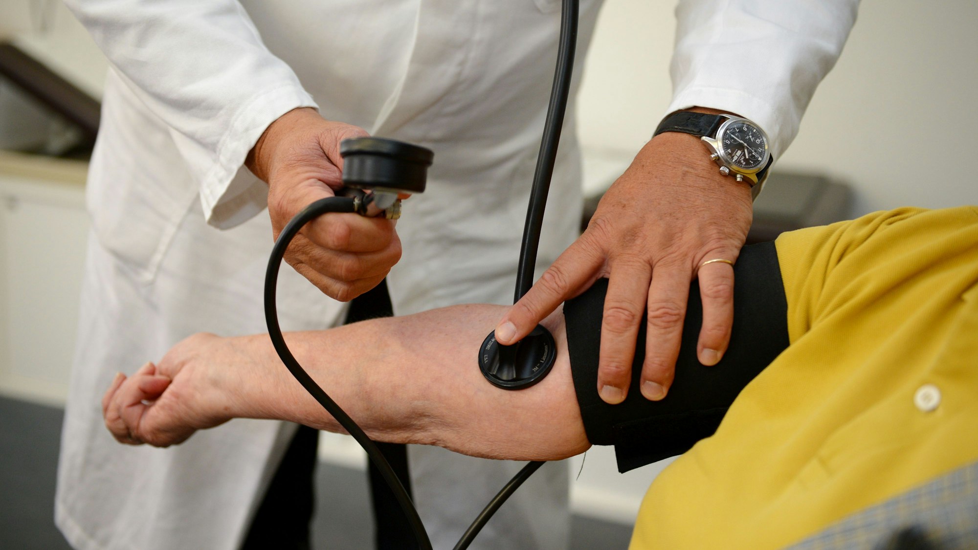 Ein Hausarzt misst in seiner Praxis den Blutdruck einer Patientin.
