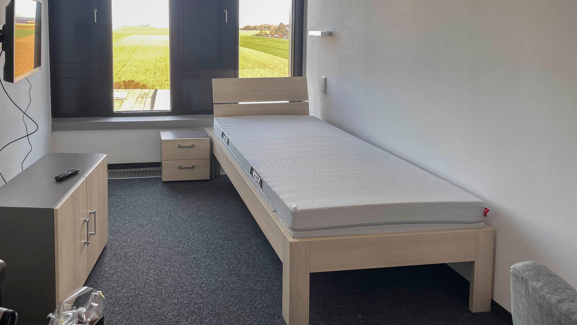 Im Ruheraum sind ein schmales Bett, ein Schrank und ein Fernsehgerät zu sehen.