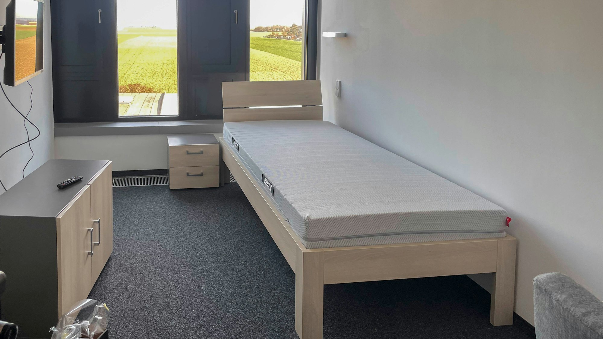 Im Ruheraum sind ein schmales Bett, ein Schrank und ein Fernsehgerät zu sehen.