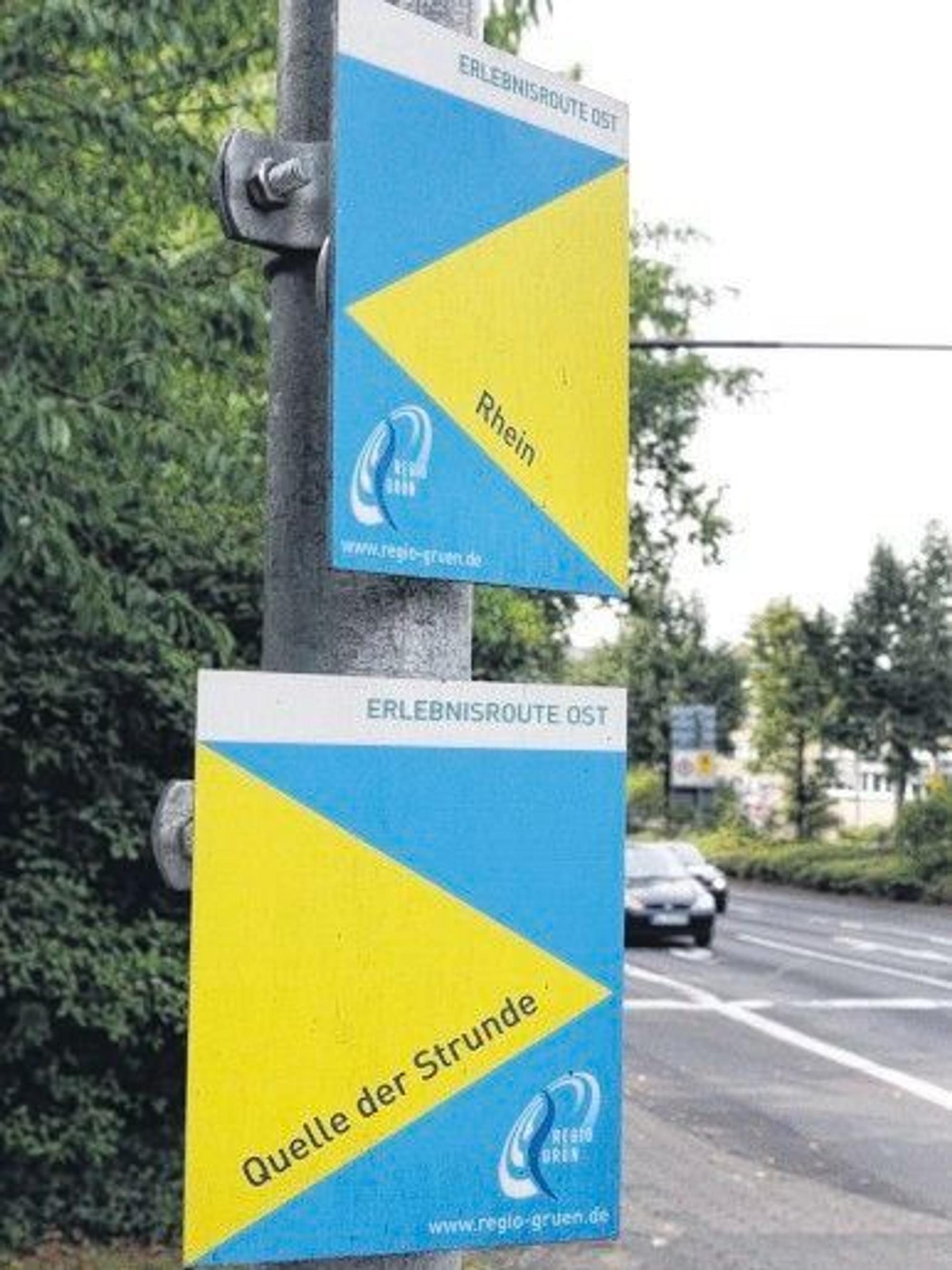 Zwei Wegweiser hängen an einem Schildemast.