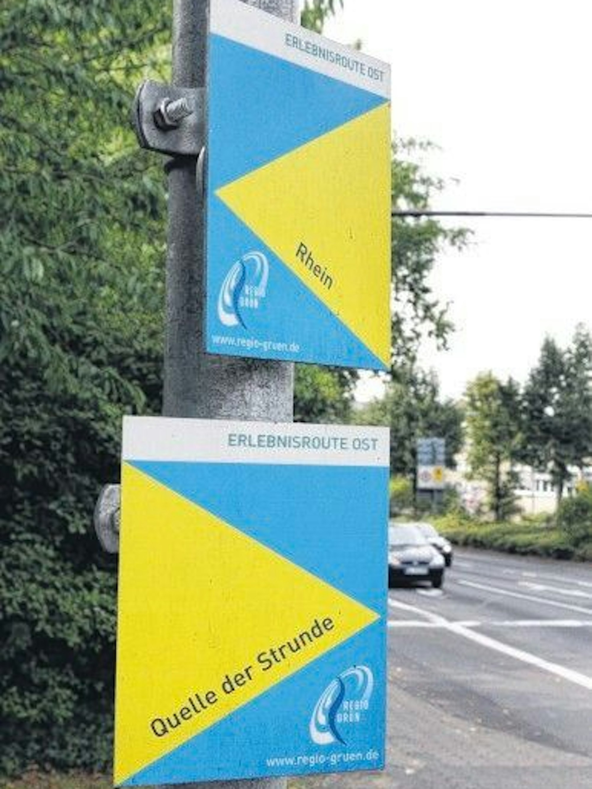 Zwei Wegweiser hängen an einem Schildemast.