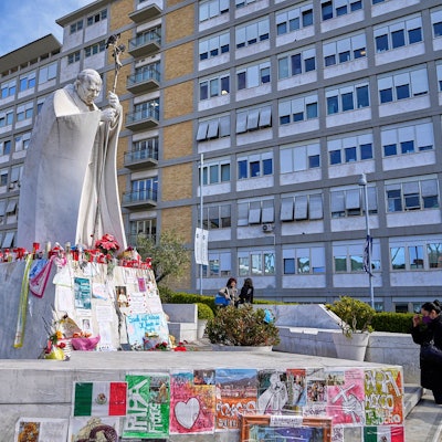 07.03.2025, Italien, Rom: Eine Frau betet vor der Statue von Papst Johannes Paul II. vor dem Agostino Gemelli, wo der Papst seit dem 14. Februar behandelt wird. Foto: Gregorio Borgia/AP/dpa +++ dpa-Bildfunk +++