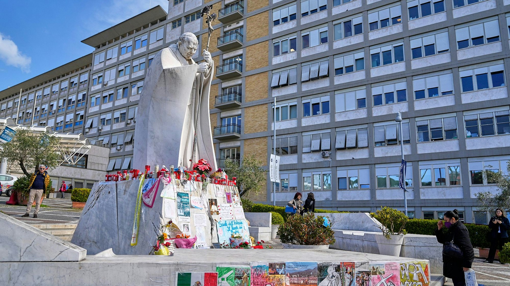07.03.2025, Italien, Rom: Eine Frau betet vor der Statue von Papst Johannes Paul II. vor dem Agostino Gemelli, wo der Papst seit dem 14. Februar behandelt wird. Foto: Gregorio Borgia/AP/dpa +++ dpa-Bildfunk +++