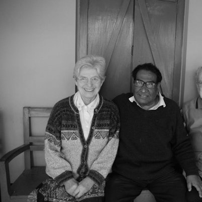 Eine Frau und zwei Männer sitzen auf einer Bank.