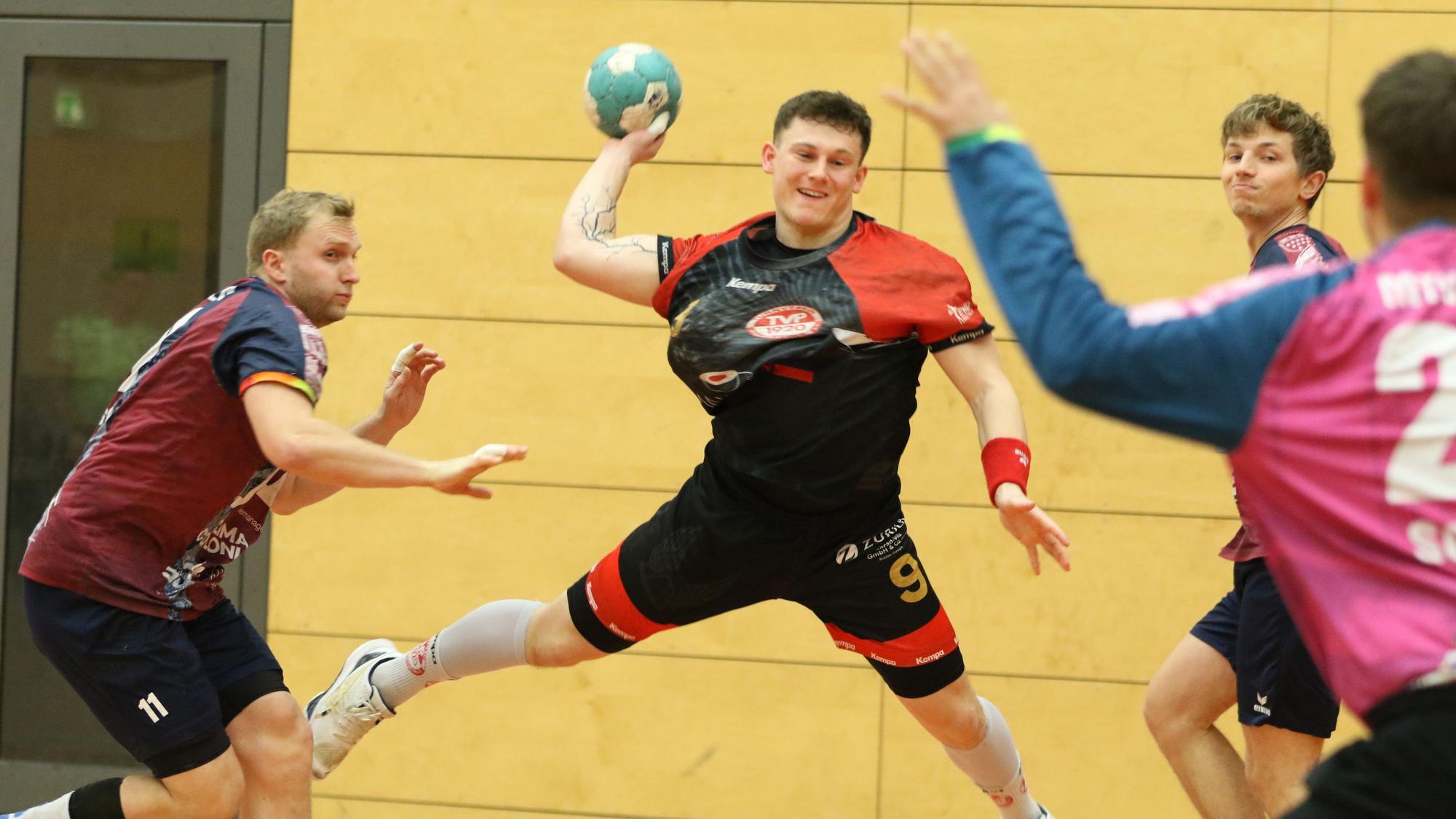 Palmersheims Marius Schmitz beim Sprungwurf, aus dem das 1:0 resultiert. Zwei Gegner stehen neben ihm und können ihn nicht stoppen. Der Torwart ist unscharf am Bildrand.