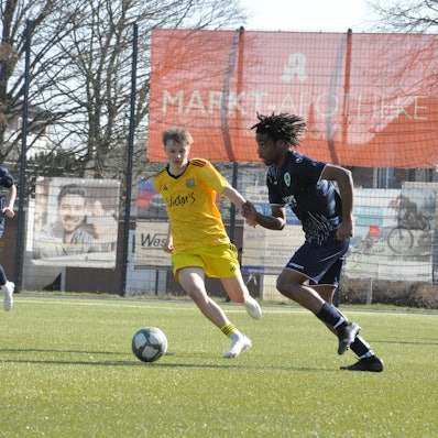 Das Foto zeigt einen Fußballer von BW Königsdorf im dunklen Trikot, der mit einem Saarbrücker Gegenspieler um den Ball kämpft