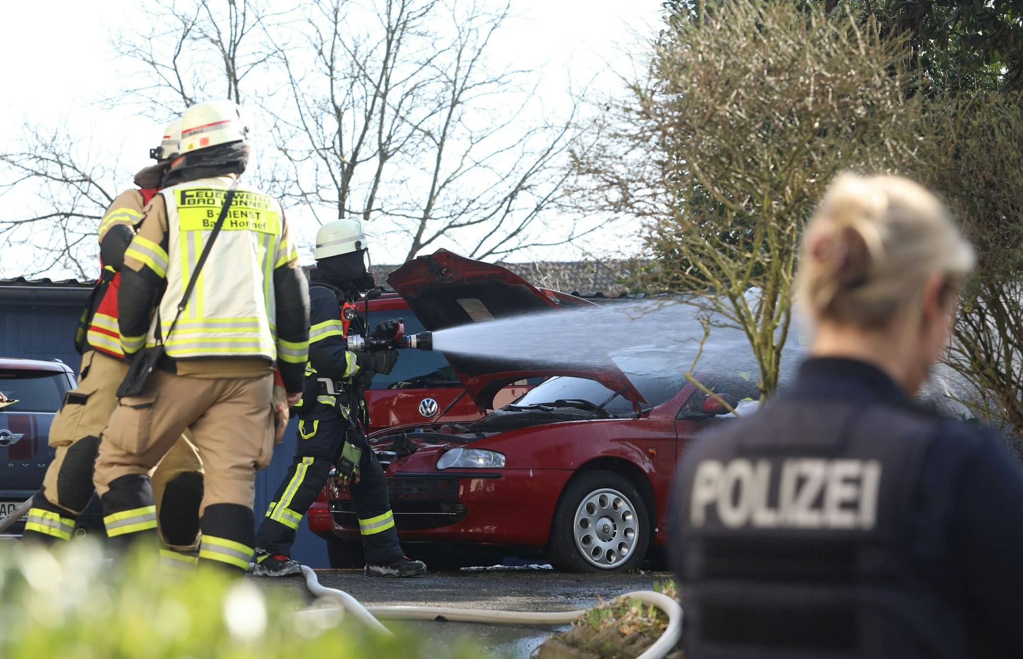 Feuerwehrleute löschen einen in Brand geratenen Pkw.