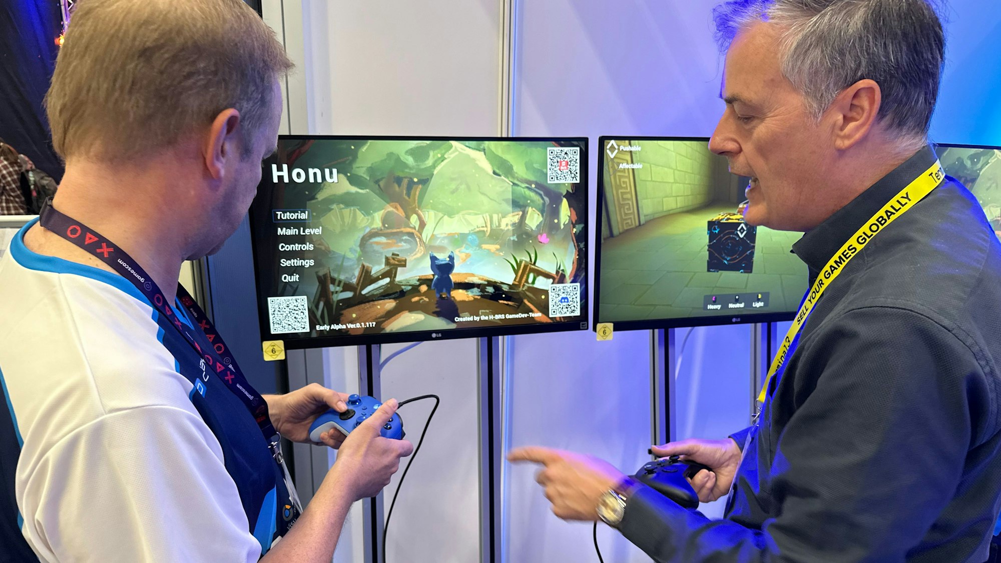 Auf einer Fachmesse sprechen ein älterer und ein junger Mann miteinander. Sie stehen vor Bildschirmen, auf denen eine Computeranimation zu sehen ist.