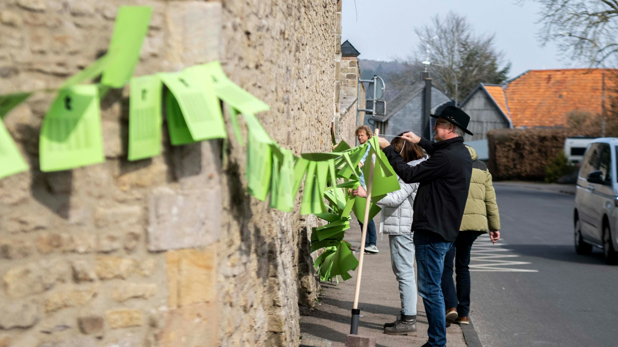 Zahlreiche grüne Blätter sind an einer Leine aufgereiht, die Demonstranten an der Klostermauer in Steinfeld befestigen.