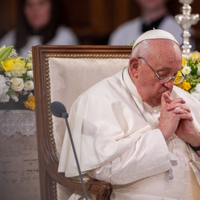 Papst Franziskus sitzt mit gefalteten Händen in der Kathedrale Notre Dame.