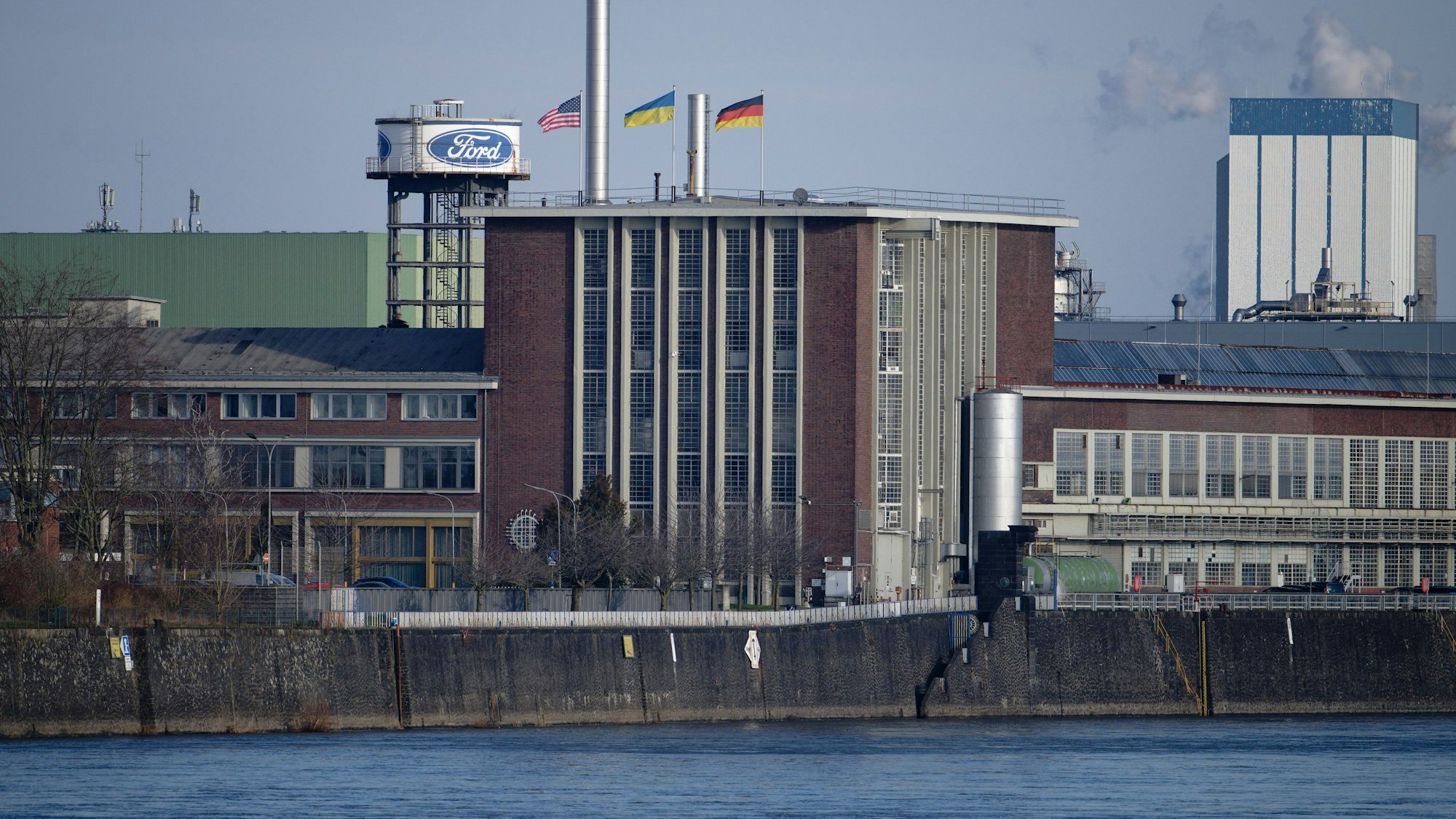 Die Flaggen der USA (l-r), der Ukraine und der Bundesrepublik Deutschland wehen über dem Dach eines Gebäudes der Fordwerke in Köln. (Archivbild)