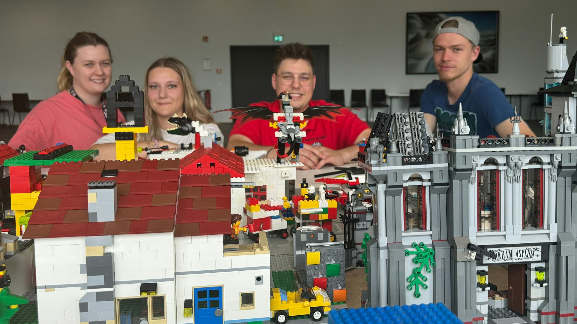 Vier junge Leute vor einer Lego-Stadt.