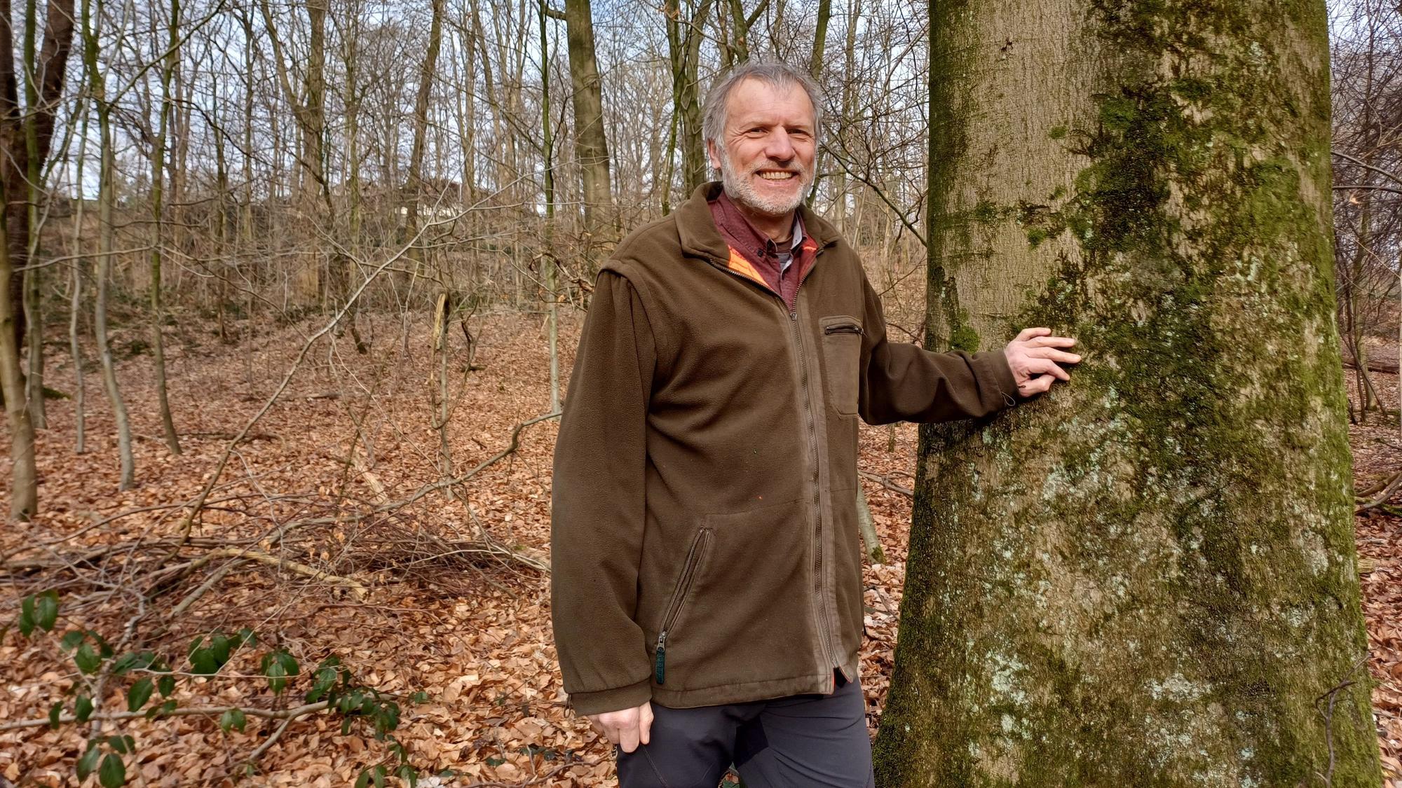 Ein Mann steh an einem Baum.