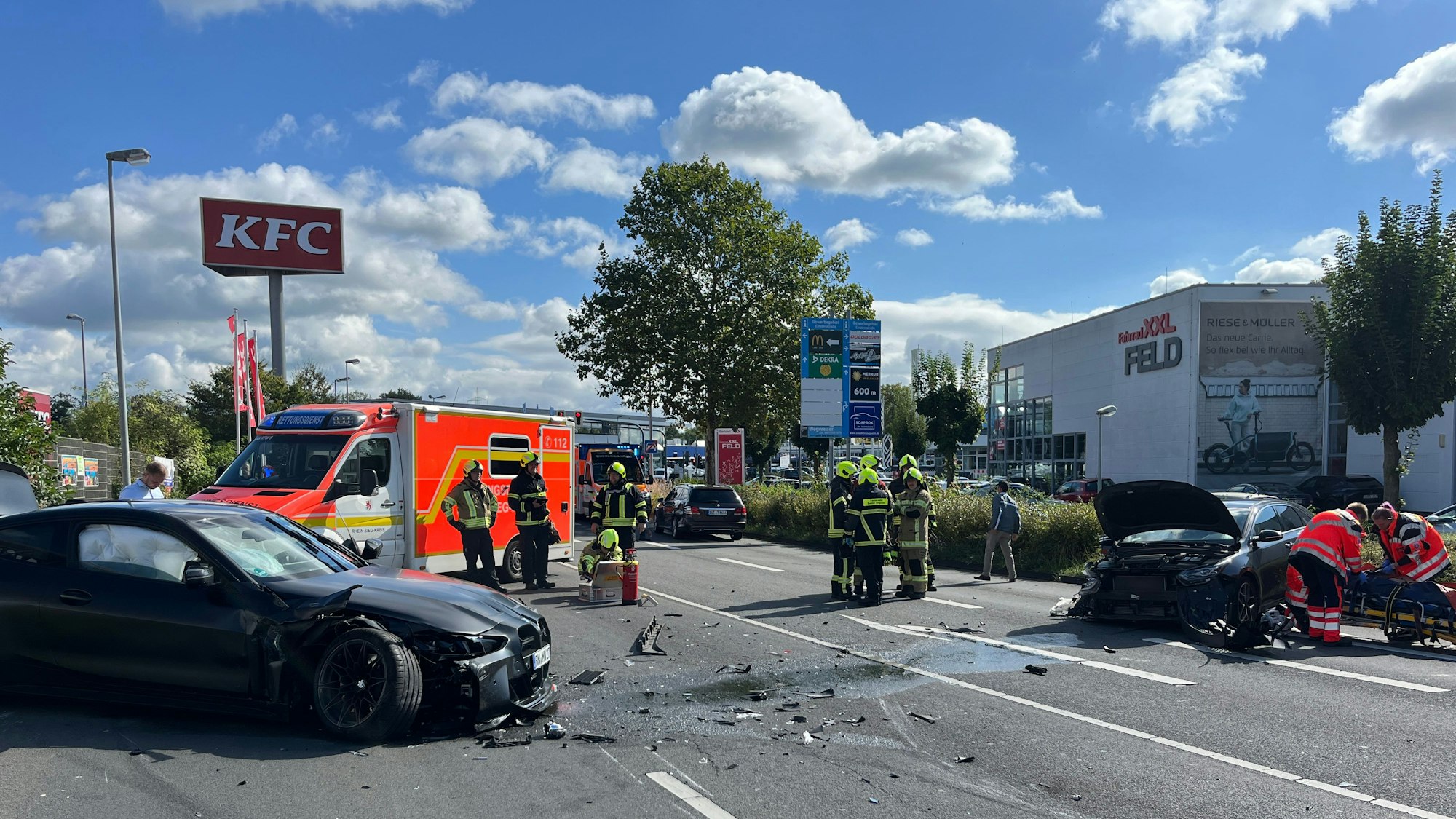 Mehrere beschädigte Autos, ein Rettungswagen und Einsatzkräfte stehen auf ener Fahrbahn