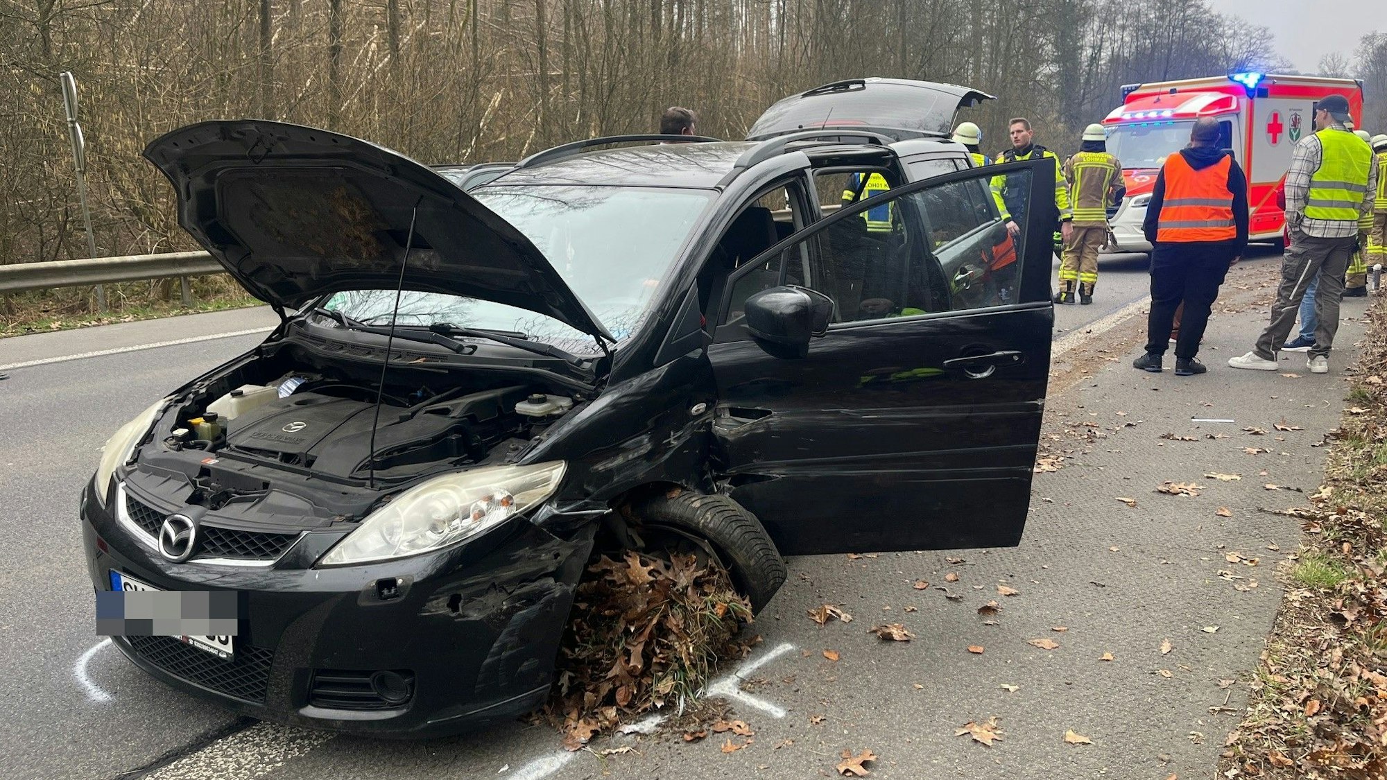 Ein schwarzer Kombi steht beschädigt auf dem Seitenstreifen neben einer Schnellstraße.