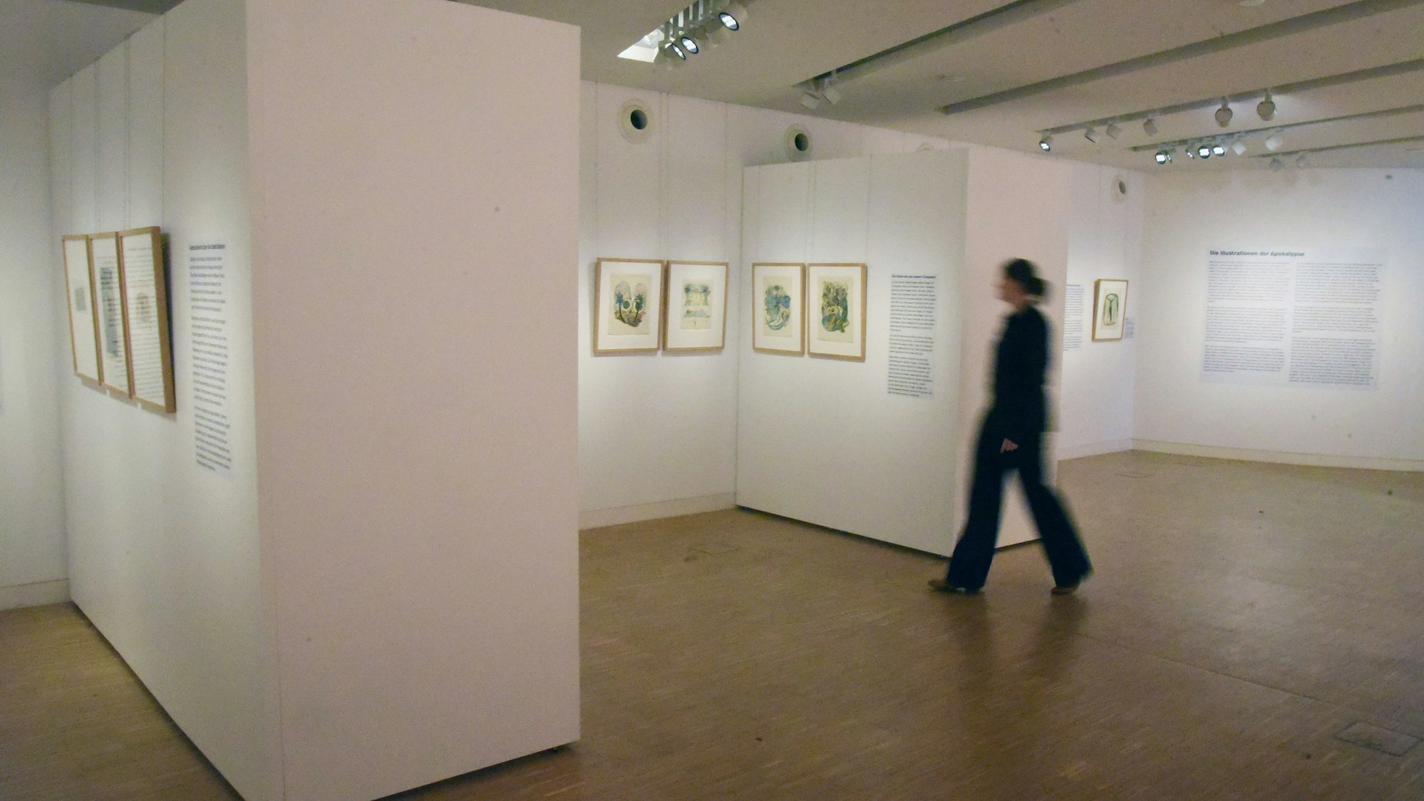 Eine Frau schreitet durch einen Ausstellungsraum.