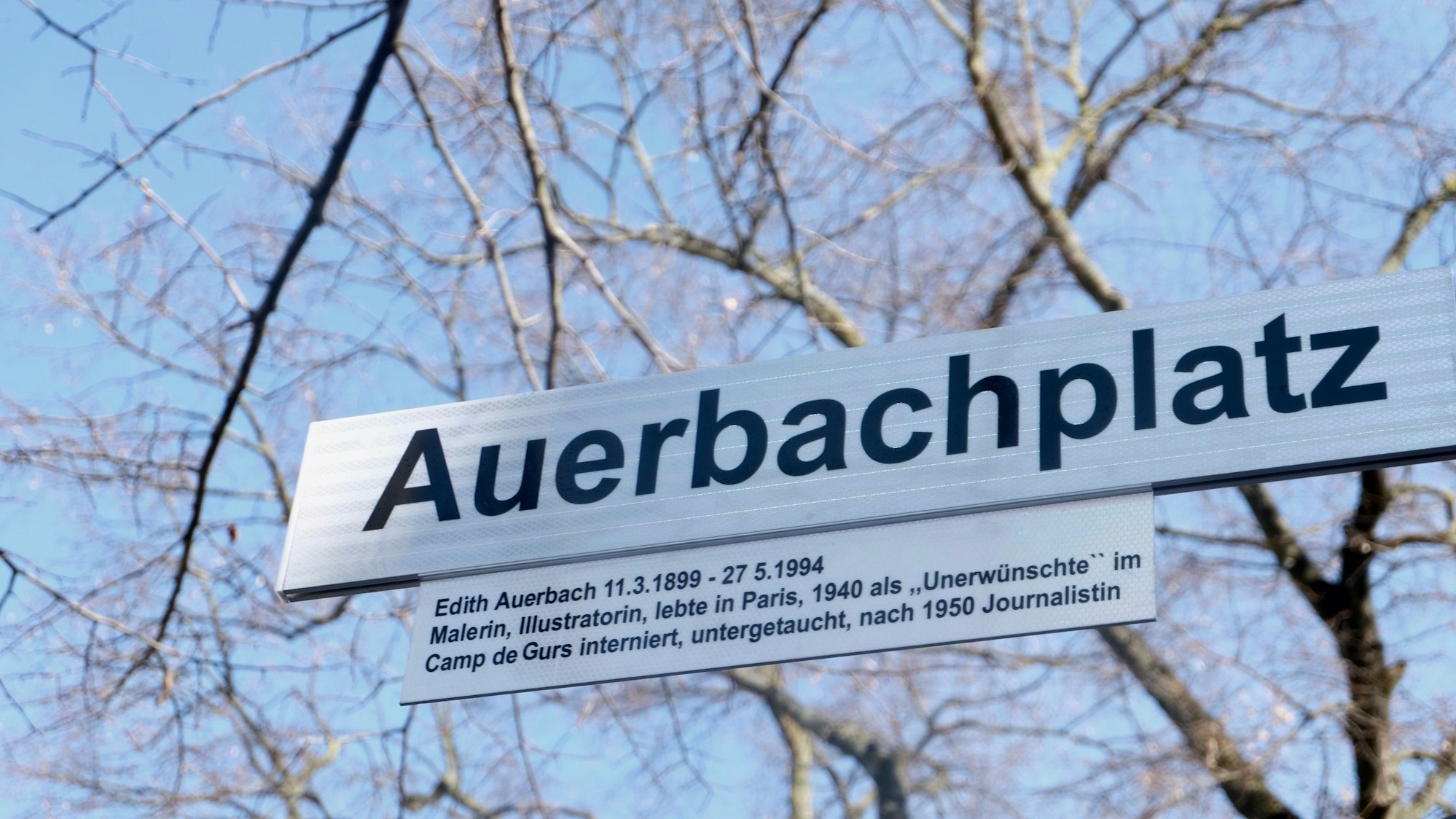 Das Straßenschild Auerbachplatz. Darunter hängt ein Erklärschild mit Informationen zur Malerin Edith Auerbach.